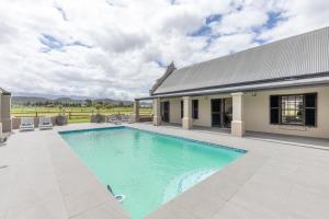 a swimming pool in front of a house at Millstream manor guest house in Robertson