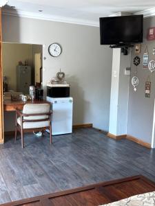 a living room with a table and a clock on the wall at Cloete Self Catering Sky Room in Ermelo