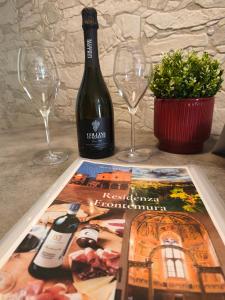 a bottle of wine next to two glasses and a magazine at Residenza Frontemura in Montefalco