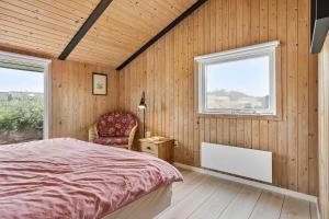 a bedroom with a bed and a chair and a window at 6606-Hvide-Sande-Arvidvej-164 in Bjerregård