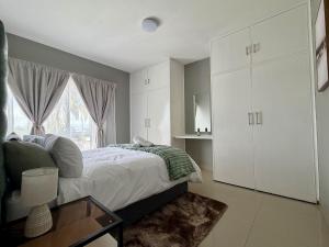 a bedroom with a bed with white cabinets and a window at 2Bedroom Apartment in Pinetown