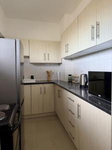 a kitchen with white cabinets and black counter tops at 2Bedroom Apartment in Pinetown