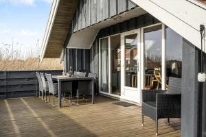 a patio with a table and chairs on a deck at 3395-Hvide-Sande-Fyrmarken-33 in Hvide Sande