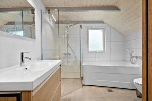 a bathroom with a tub and a sink and a shower at 3395-Hvide-Sande-Fyrmarken-33 in Hvide Sande +49 photos