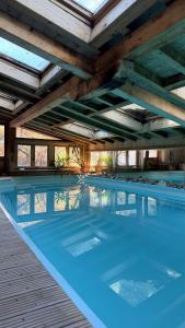 a large swimming pool with blue water in a building at Maison du Bourg in Samoëns