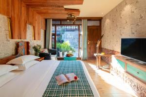 a bedroom with a large bed with a flat screen tv at Sunlit Snow Mountain Z Naxi Ethnic Style Courtyard in Lijiang