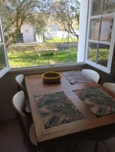 a wooden table with chairs around it with a window at L' amandier in Teyran