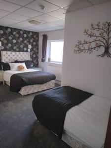 a bedroom with two beds and a tree on the wall at Le Maitre in Southport