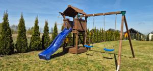 a playground with two swings and a slide at Karmelowy Zakątek in Darłowo