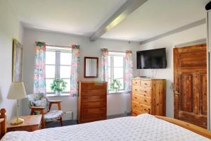 a bedroom with a bed and a tv and windows at 6306-Stege-Hjelmvej-24 in Stege