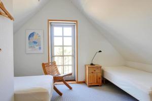 a room with two beds and a chair and a window at 6306-Stege-Hjelmvej-24 in Stege