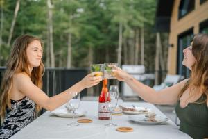 two women sitting at a table with wine glasses at Chalet Le Solem Golf et Spa in Saint-Faustin