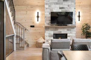 a living room with a fireplace and a flat screen tv at Chalet Le Solem Golf et Spa in Saint-Faustin