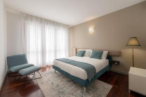 a bedroom with a large bed and a blue chair at Como Prestige Centro Apartment By Icon7 Luxury in Como