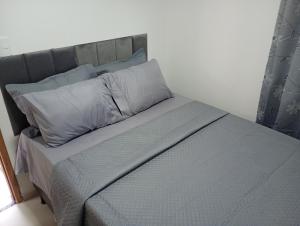 a bed with a gray headboard and pillows at top Suites in Saquarema