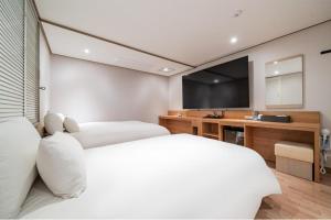 a bedroom with two beds and a flat screen tv at CENTRO HOTEL - 안양iT단지, 군포제일공단 in Anyang
