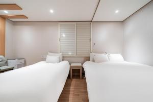 two beds in a room with white walls at CENTRO HOTEL - 안양iT단지, 군포제일공단 in Anyang