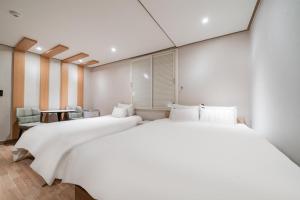 two beds in a room with white walls at CENTRO HOTEL - 안양iT단지, 군포제일공단 in Anyang