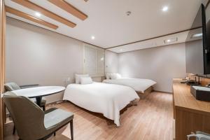 two beds in a room with a table and a tv at CENTRO HOTEL - 안양iT단지, 군포제일공단 in Anyang +29 photos