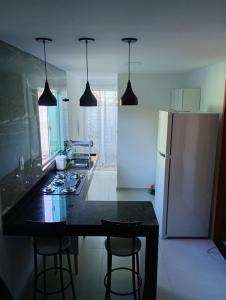 a kitchen with a black counter top and a refrigerator at top Suites in Saquarema