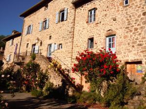 a stone building with flowers in front of it at Mas Casta Néa in Thueyts