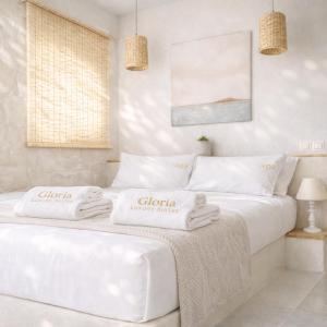 two beds in a white room with towels on them at Gloria Luxury Suites in Kallithea Halkidikis