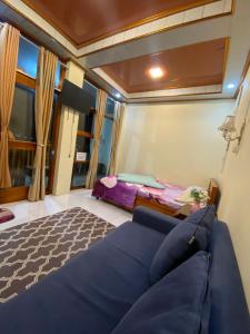 a living room with a blue couch and a bed at Agriya Lubis 2 room in Diyeng