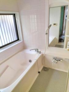 a white bath tub in a bathroom with a window at さくらVillaCOAST in Futtsu +12 photos