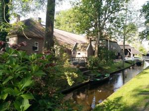 a house on a river with a boat in the water at De Kazerne - Kiersche wijde in Wanneperveen