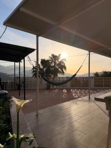 a hammock on a patio with the sunset in the background at Casa rural Cristina- Piscina climatizada in Málaga