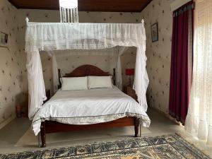 a bedroom with a canopy bed with white sheets and pillows at Angel's place in Kabale
