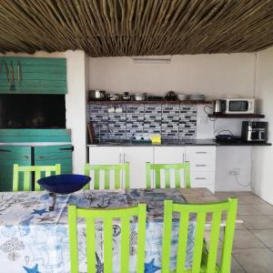 a kitchen with a table with four chairs and a blue bowl at The Tides Holiday Home in St. Helena Bay