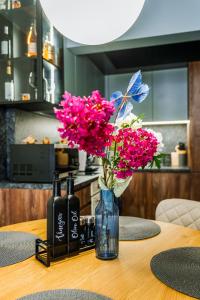 a table with a vase with pink flowers and two bottles at The Nest in Ruse +35 photos