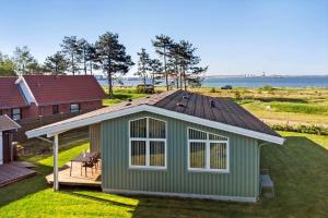 a green house with a roof and a deck at 8205-Vordingborg-Strandparken-12 in Vordingborg