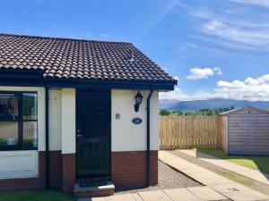 a small house with a green door and a fence at Calluna Cottage in Aviemore