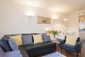 a living room with a black couch and two chairs at Calluna Cottage in Aviemore