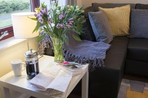 a vase of flowers on a table next to a couch at Calluna Cottage in Aviemore