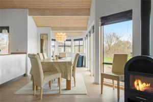 a dining room with a table and chairs and a fireplace at 1306-Stege-Kaerhogevej-64 in Stege
