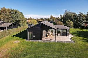 a small black house on a grass field at 1306-Stege-Kaerhogevej-64 in Stege