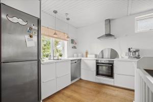 a kitchen with white cabinets and a stainless steel refrigerator at 4033-Stege-Kirkebakken-33 in Stege