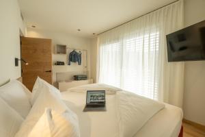 a bedroom with a laptop on a white bed at Etra Suites & Apartments in Riva del Garda
