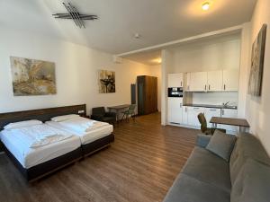 a bedroom with a bed and a couch and a kitchen at TRUST Boardinghouse in Stuttgart