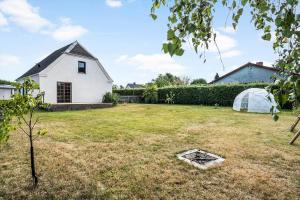 a yard with a white house and a greenhouse at 4019-Stege-Udbyvej-15 in Stege