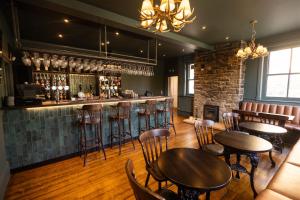 a restaurant with tables and chairs and a bar at Hadrians Hotel in Chesters