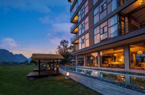 a building with a swimming pool and a gazebo at Meadowscape Resort at Yulong River - Karst Views & Infinity Pool & Tickets Reservation Service & Free Laundry in Yangshuo