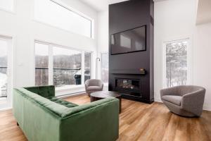 a living room with a green couch and a fireplace at Chalet Mysa Spa Lac access Firepit pit SKI in Saint Come
