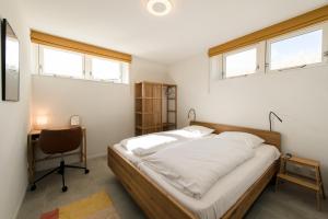 a bedroom with a bed and a desk and windows at Hestia (8p) in Nes