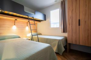 a room with two beds and a ladder next to a window at Punta Falconera camping & village in Caorle +60 photos