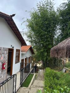 a white house with a thatched roof and a walkway at Chalé Vila Catarina in Ouro Preto