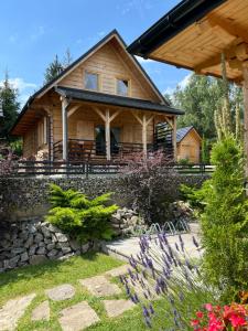 a log cabin with a porch and flowers at Borowikowe Zacisze drewniane domy z kominkami in Falsztyn